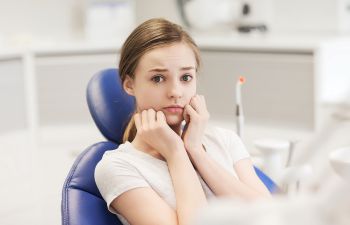 A teenage girl with dental anxiety at dental appointment.