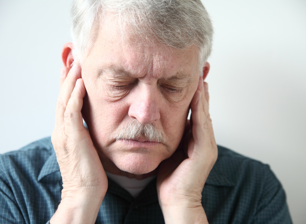 jaw pain | older man holds both hands to his upper jaw 
